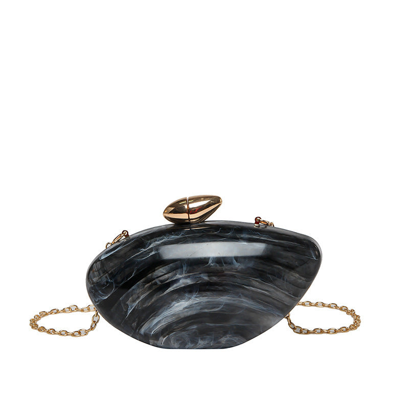Oval shell acrylic evening bag in black with gold chain, perfect for evening occasions.