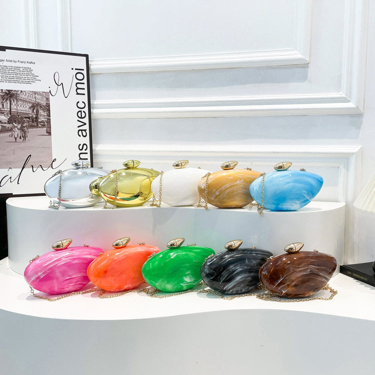Oval shell acrylic evening bag collection in various colors displayed on a shelf.