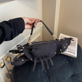 Korean style personalized messenger bag in black with unique lobster design and rivets, held by a person.