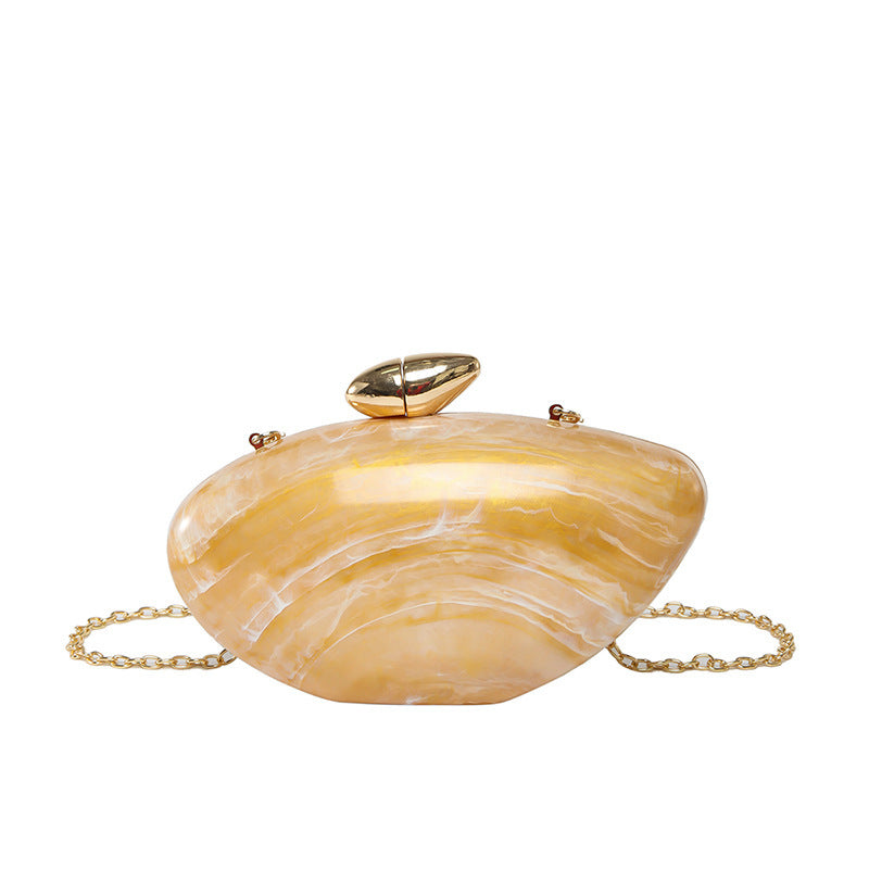 Oval shell acrylic evening bag in yellow with a gold clasp and chain.